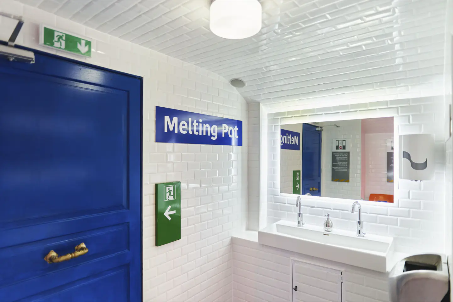Espace sanitaires carrelé blanc avec porte bleue au Melting Pot Bagnolet