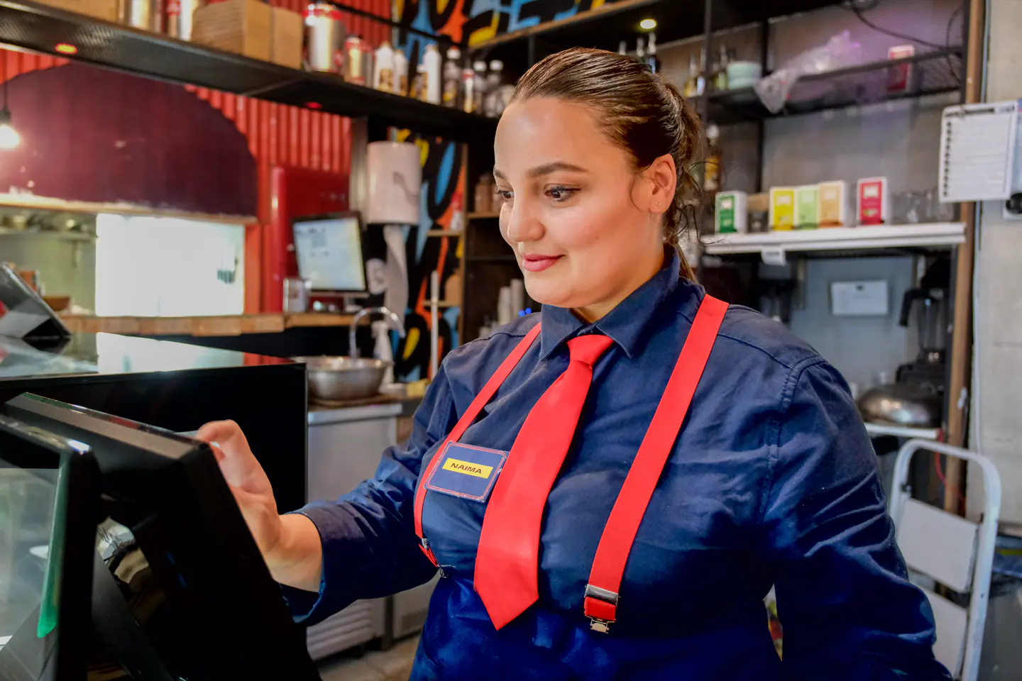 Équipière Melting Pot en uniforme aidant à la borne de commande