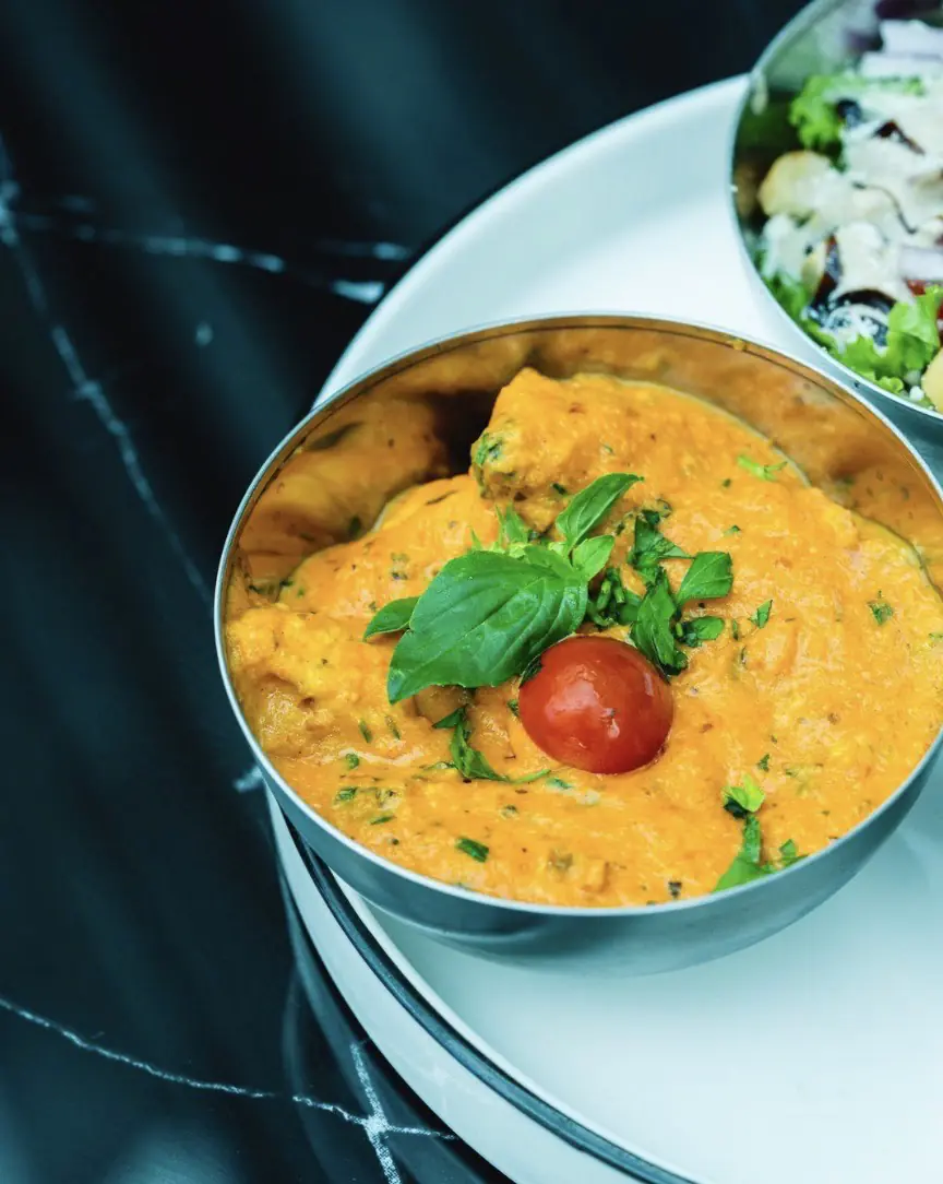 Curry indien orangé servi dans une assiette creuse