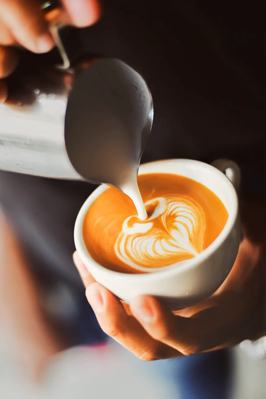 Barista versant un latte art dans une tasse